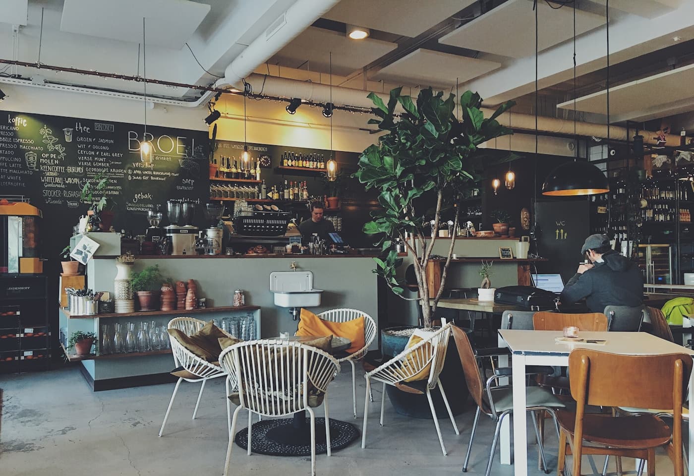 Commercial interior of Café N°7 in Agadir showing brushed brass counter accents, travertine tables, and curved plaster seating booths